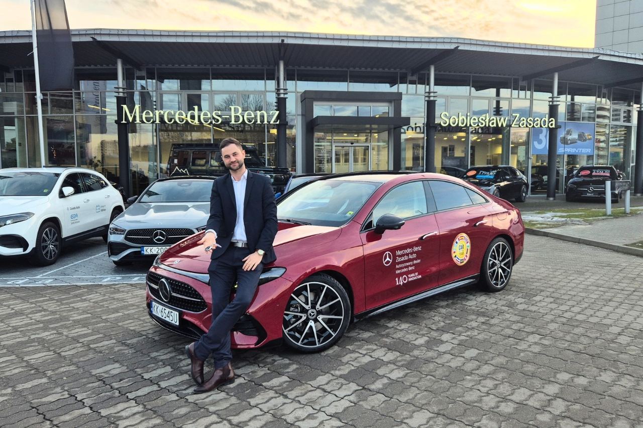 na zdjęciu widać osobę, kt&oacute;ra jest oparta o nowe CLA Spalinowe i trzyma kluczyki przed salonem Mercedes-Benz Zasada Auto